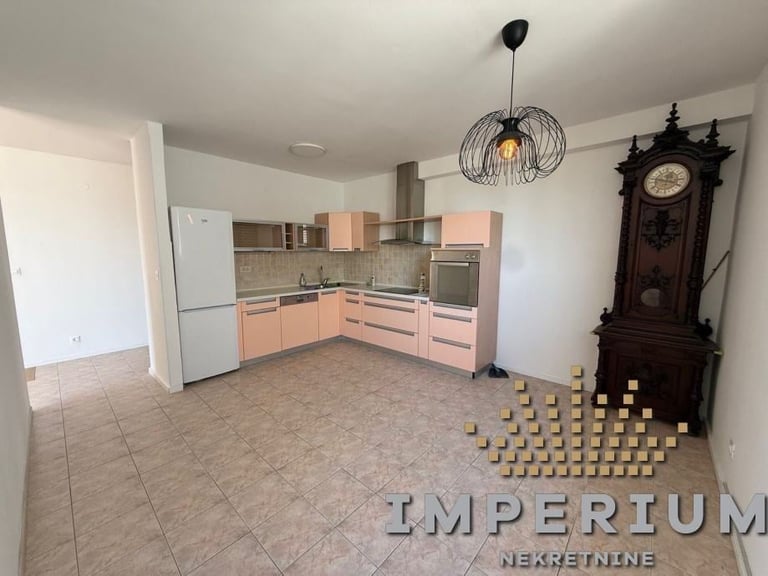 Empty kitchen with pink cabinetry, white refrigerator, and a wooden grandfather clock against the wall
