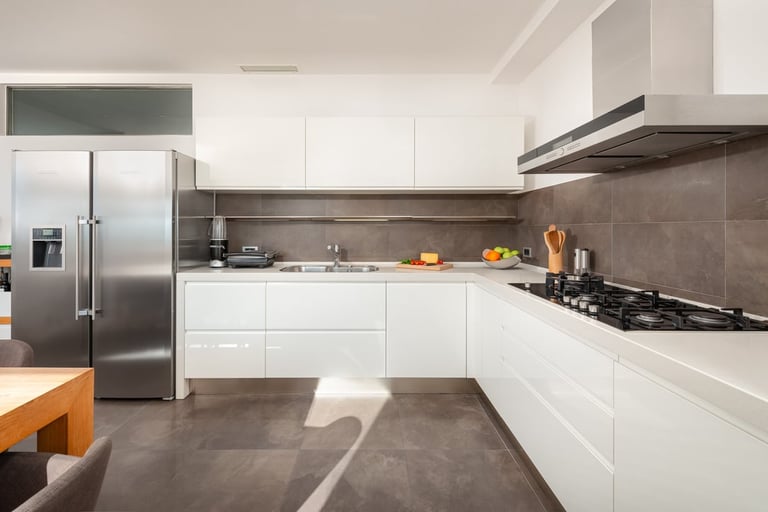 Modern kitchen with white cabinetry, stainless steel appliances, gray tile backsplash, and dark polished concrete flooring