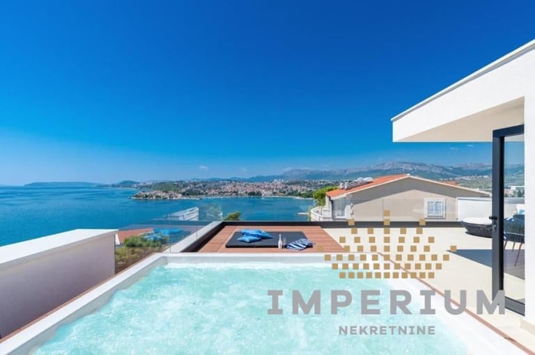 Luxury rooftop pool with turquoise water overlooking Mediterranean coastline and mountains under clear blue sky
