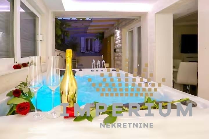 Luxury spa bathtub display with blue water, champagne bottle, flowers, and candles in an upscale bathroom setting