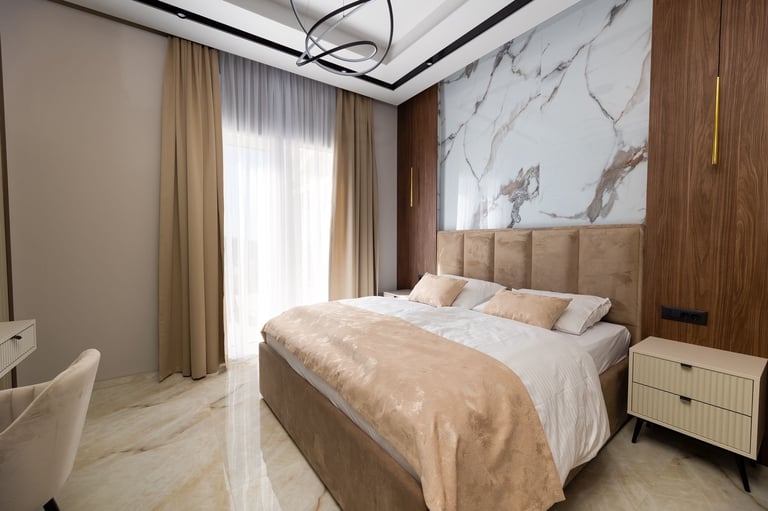 Modern bedroom with upholstered bed, marble accent wall, wooden paneling, beige curtains, and contemporary ceiling fixture