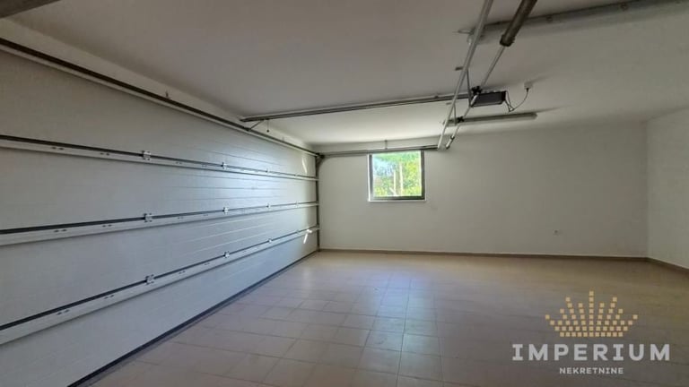 Empty residential garage with closed white door, concrete floor, and small window on the wall.