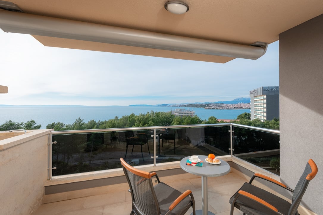 Balcony with modern furniture overlooking a coastal bay and city skyline