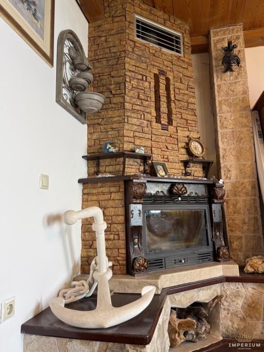 Fireplace with exposed brick, decorative stone sculpture, ornamental items on mantel, and traditional hearth decor