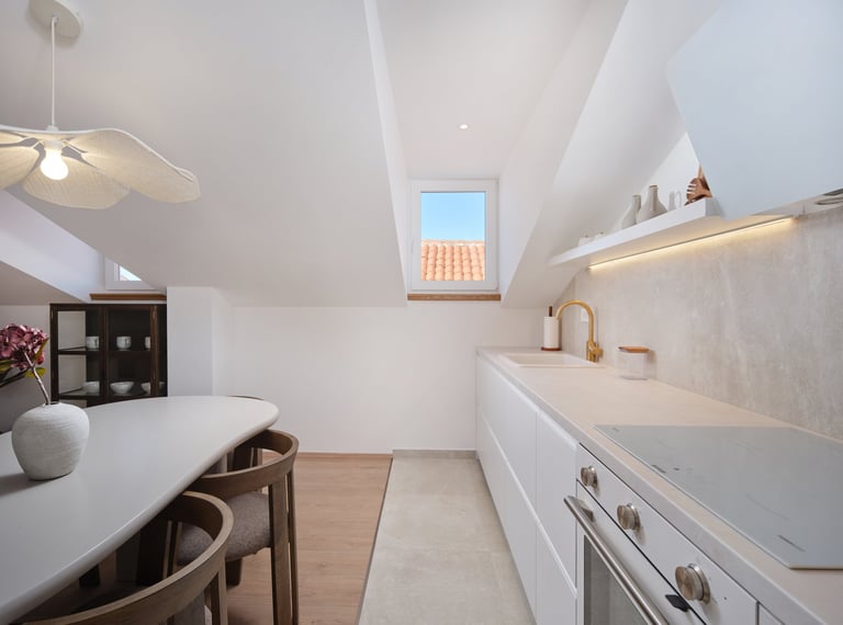 Modern white kitchen and dining area with skylight, wooden flooring, and contemporary furnishings
