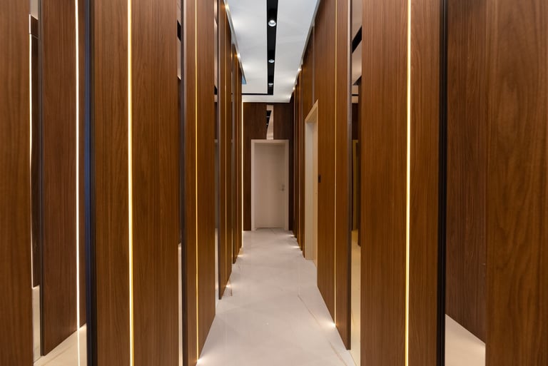 A long corridor with wooden panel doors on both sides and recessed ceiling lights