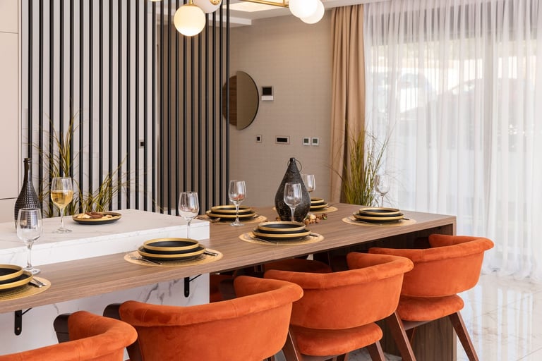 Modern dining room with orange upholstered chairs, wooden table, gold place settings, and contemporary pendant lights overhead
