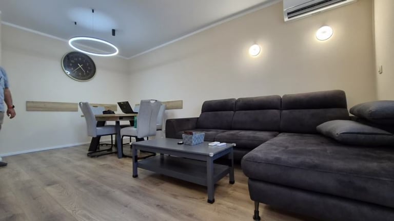Modern living room with black sectional sofa, dining table with chairs, black coffee table, and recessed lighting on white walls