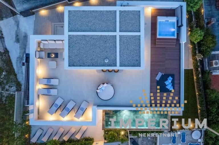 Aerial view of modern luxury backyard with pool, lounge chairs, lighting, and deck seating