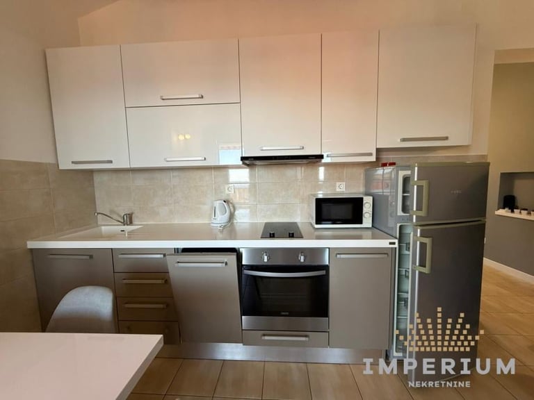 Modern kitchen with white and stainless steel cabinets, built-in oven, microwave, dishwasher, and stainless steel refrigerator