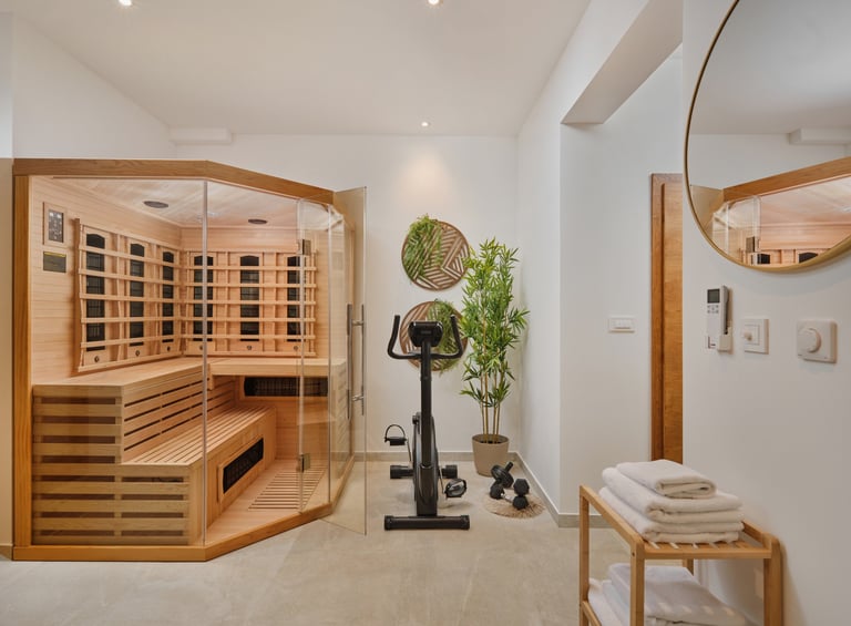 Modern spa bathroom with wooden infrared sauna, stationary bike, potted plants, and towel rack