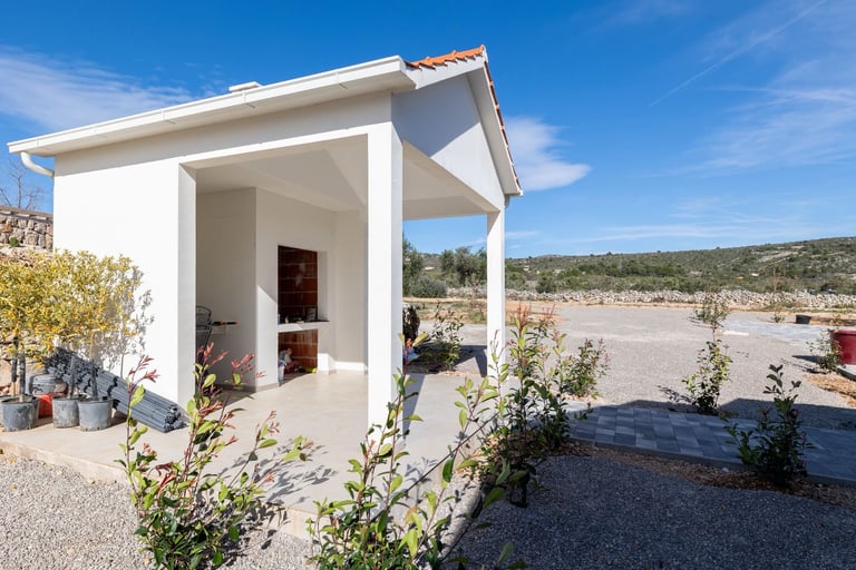 White modern shed with covered porch in arid landscape under clear blue sky