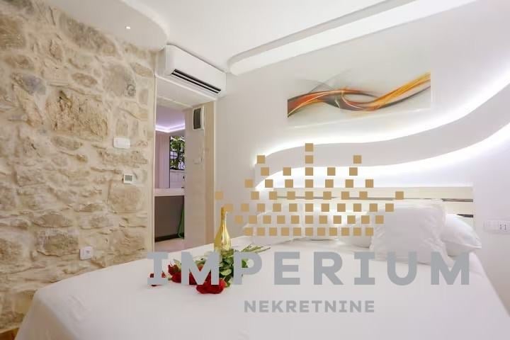 Modern spa reception area with white desk, stone accent wall, decorative wooden wall art, and ambient lighting