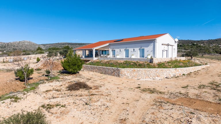 White modern house with orange roof in arid desert landscape under clear blue sky