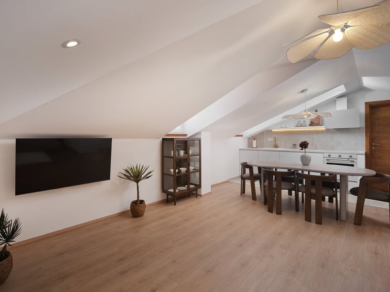 Modern attic loft with white walls, wooden flooring, mounted TV, dining table, kitchen area, and skylights