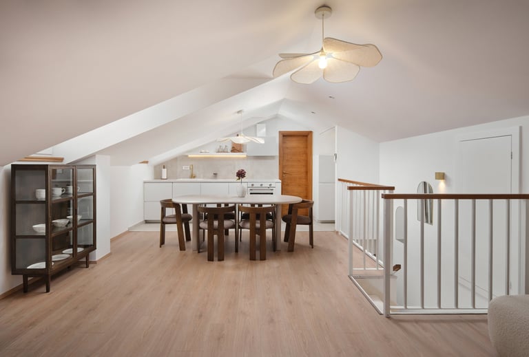Modern loft space with dining table, wooden floors, white walls, ceiling fan, and staircase railing