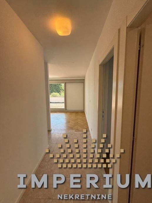 Modern hallway with cream walls, geometric floor pattern, rounded ceiling light, and doors on right side