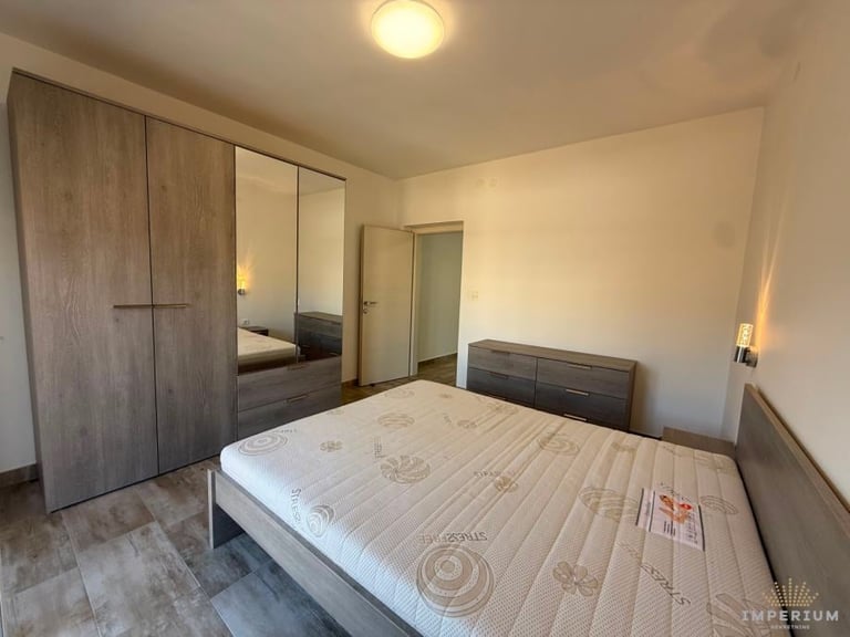 Modern bedroom with double bed, large wardrobe with mirror, and built-in storage, bathed in warm lighting