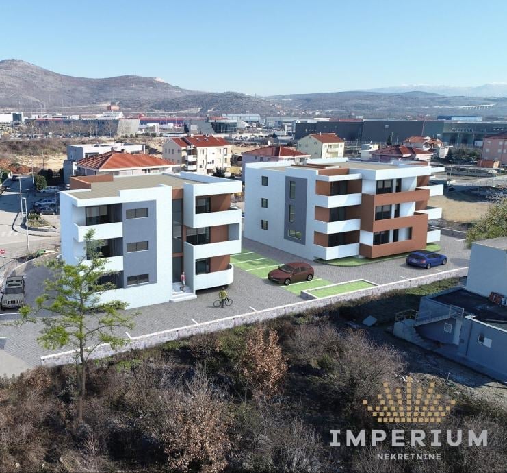 Modern apartment complex with white and orange buildings in urban setting with mountains in background