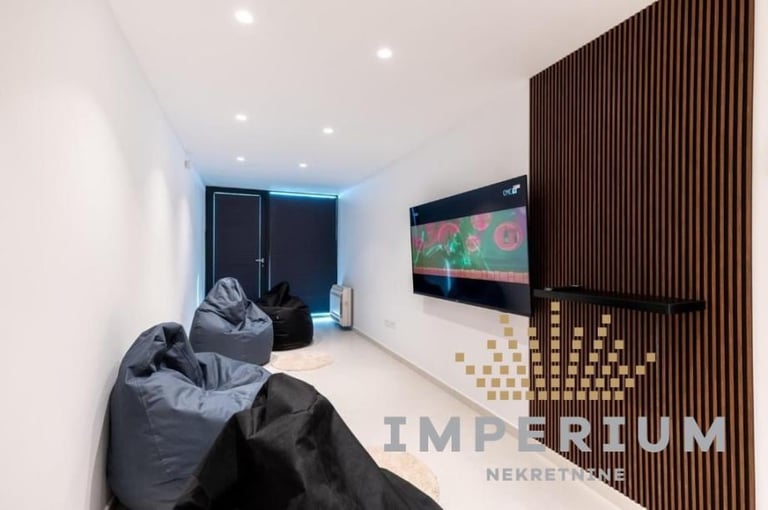 Modern home theater room with black bean bag chairs, wall-mounted TV, and dark wood slat accent wall with ambient lighting
