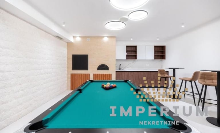 Modern game room with turquoise pool table, white brick walls, pendant lighting, and bar seating area