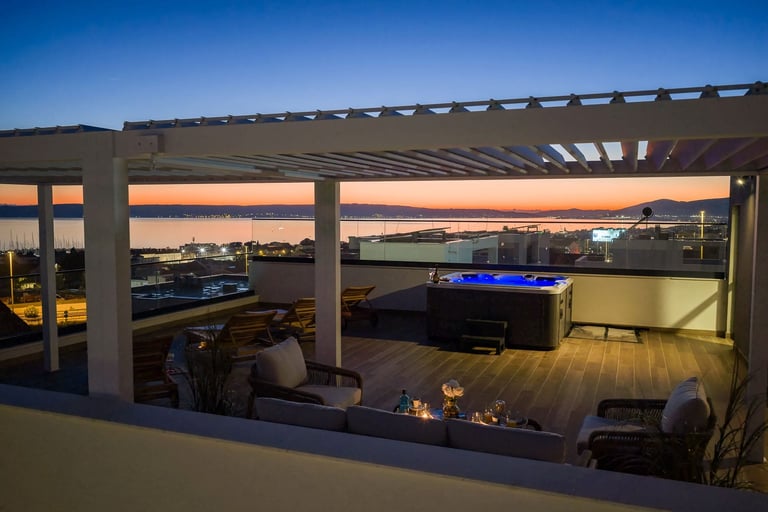 Modern rooftop patio at dusk with pergola, firepit, and water view at sunset