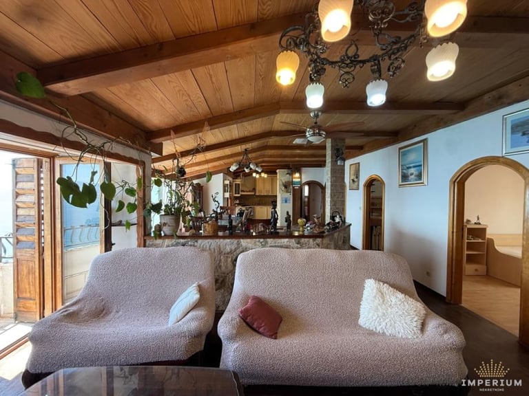 Modern living room with gray lounge chairs, wooden ceiling and bar, decorative lighting, potted plants, and mirrored shelving