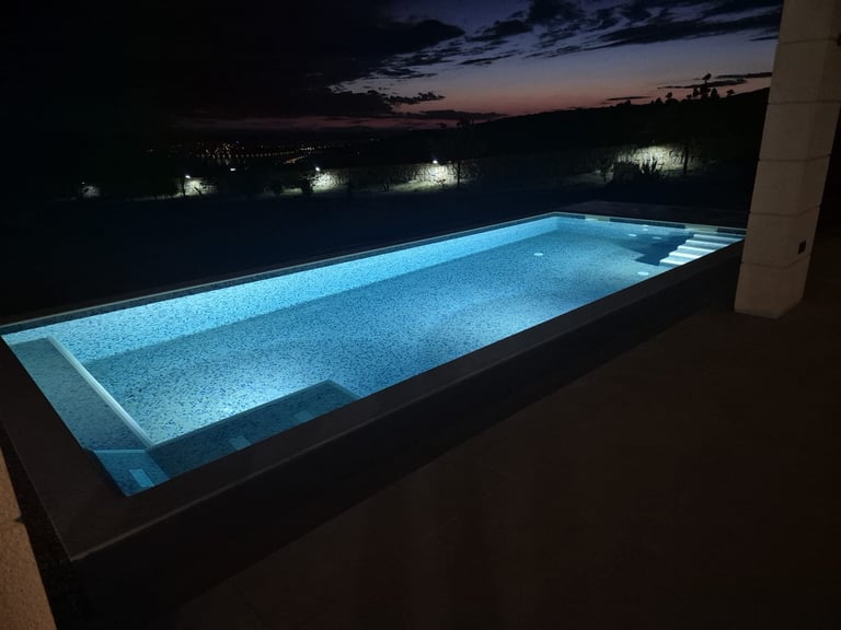 Illuminated rectangular swimming pool at dusk with blue LED lighting