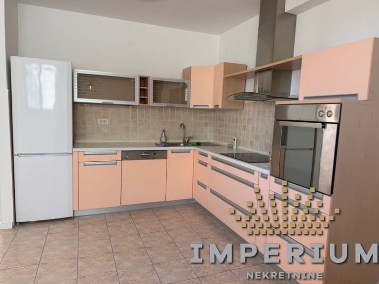 Modern kitchen with peach and gray cabinetry, stainless steel appliances, and tiled backsplash in an unfurnished apartment.