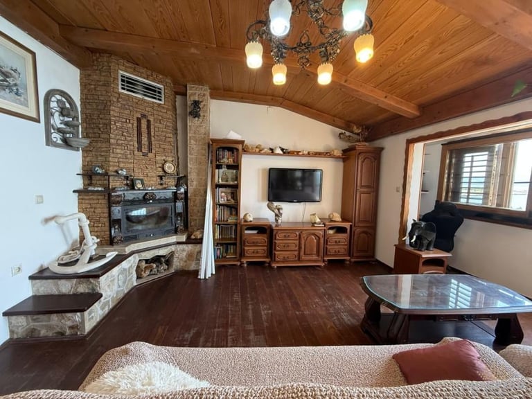 Cozy home interior with wood ceiling, fireplace, TV entertainment area, round coffee table, and comfortable seating