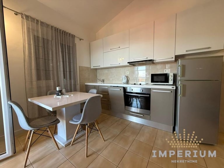Modern kitchen with white cabinetry, stainless steel appliances, dining table, and beige curtains