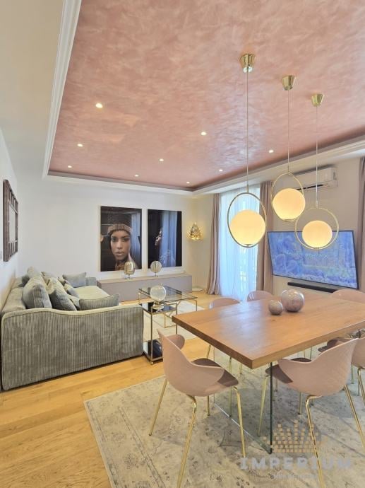 Modern open-concept living room and dining area with wood table, upholstered sofa, pendant lights, and textured ceiling