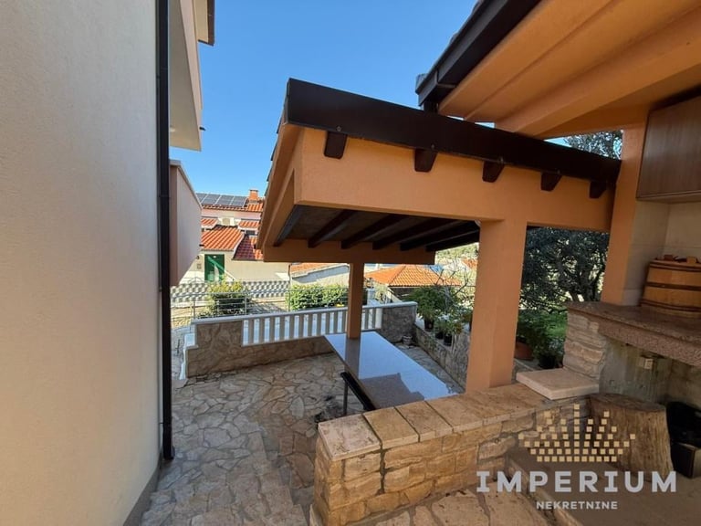 Covered patio with orange pergola structure, stone flooring, and views of surrounding hillside landscape
