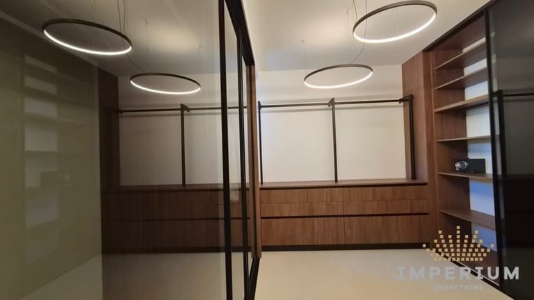 Modern interior office or retail space with dark wood cabinetry, glass partitions, circular ceiling lights, and white walls