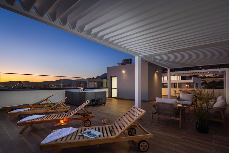 Modern rooftop terrace at dusk with wooden loungers, pergola, and seating area overlooking a city and waterfront