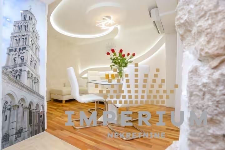 Modern dental office reception area with curved ceiling, wood flooring, white furniture, and architectural photograph on wall