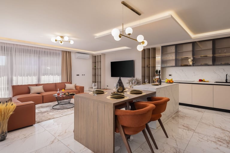 Modern open-plan apartment interior with terracotta sofa, kitchen island, wall-mounted TV, and contemporary lighting fixtures in neutral tones
