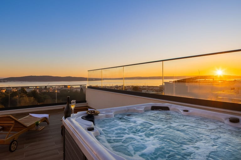 Hot tub on rooftop terrace with sunset ocean view and lounge chair at golden hour