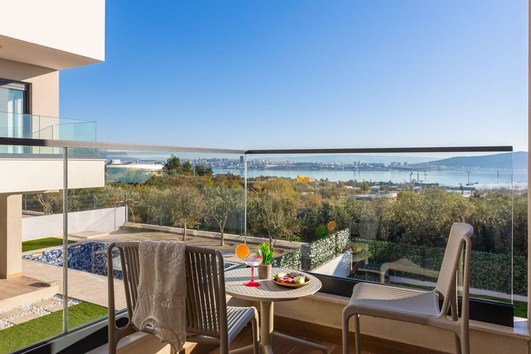 Modern terrace with outdoor dining furniture overlooking trees and bay water view on clear day