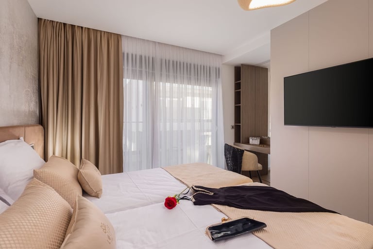 Modern bedroom with twin beds, beige curtains, wall-mounted TV, and minimalist decor in neutral tones