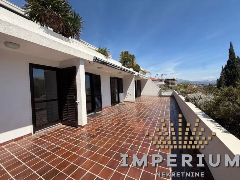 Modern white house with terracotta tile terrace, palm trees, and mountain views under clear blue sky