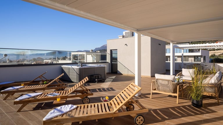 Rooftop terrace with wooden lounge chairs, mountain views, and modern residential buildings in background