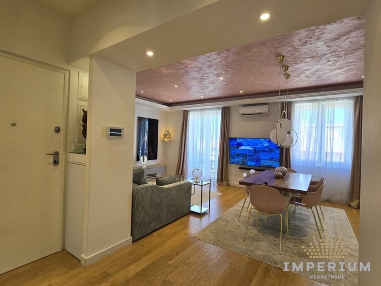 Modern apartment interior with living room, TV, dining area, and large windows with natural light and wooden flooring