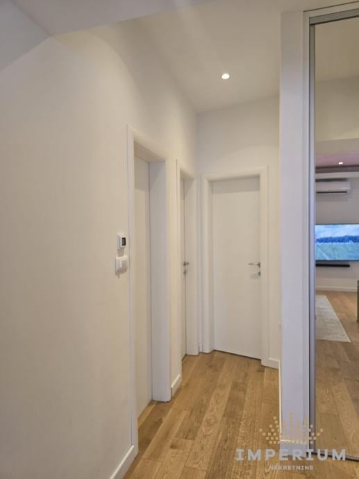 Modern hallway with white doors and wooden flooring leading to an open living area with ocean view