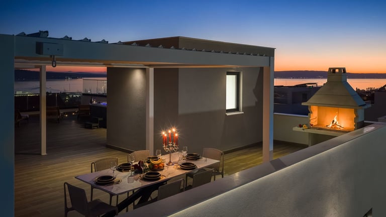 Modern rooftop pavilion at dusk with dining area, fireplace, and city skyline view at sunset