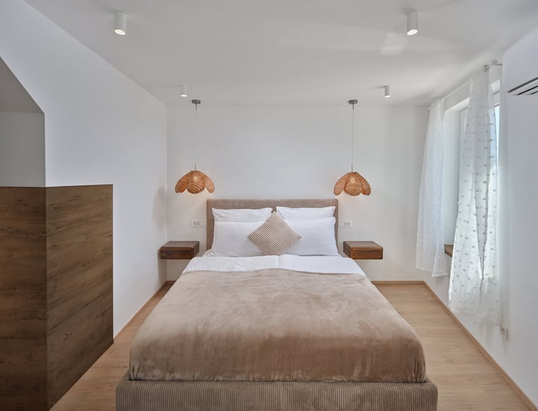 Modern minimalist bedroom with wooden bed, white walls, warm pendant lights, and hardwood flooring