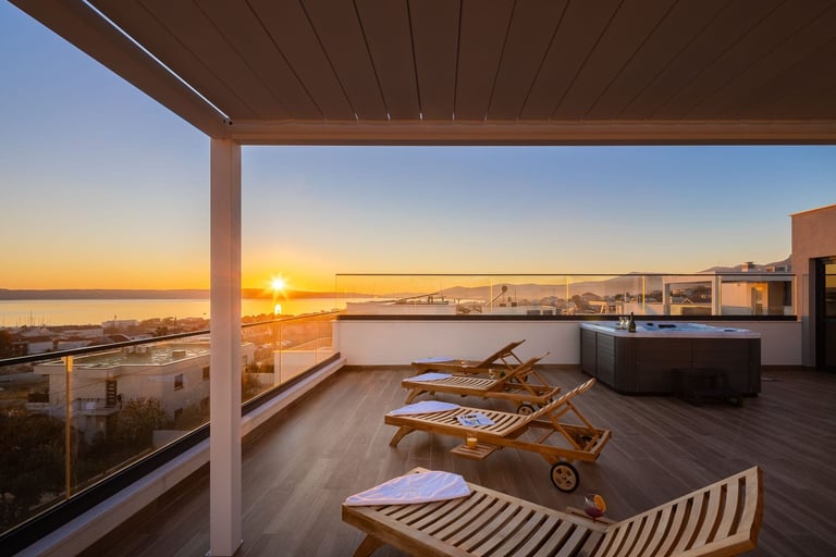 Modern rooftop terrace with wooden lounge chairs overlooking a sunset harbor view with water and distant city skyline