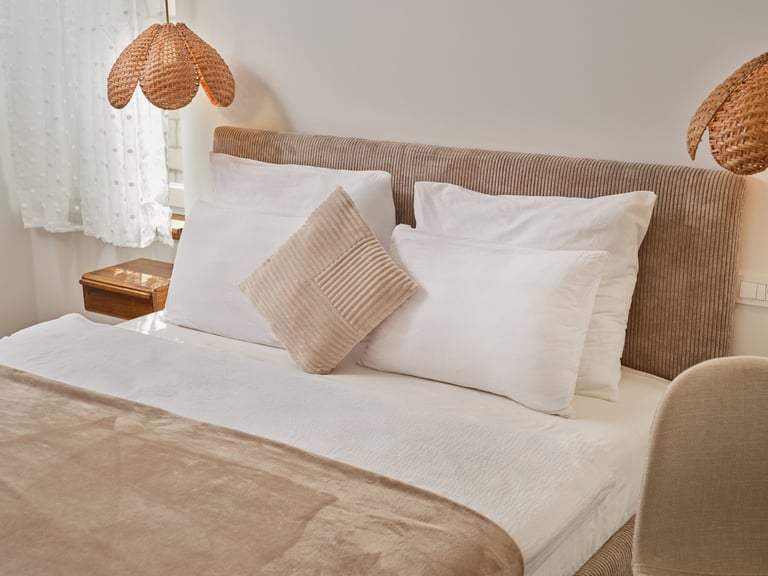 Modern bedroom with white bed, beige pillows, woven pendant lights, and neutral earth-tone decor