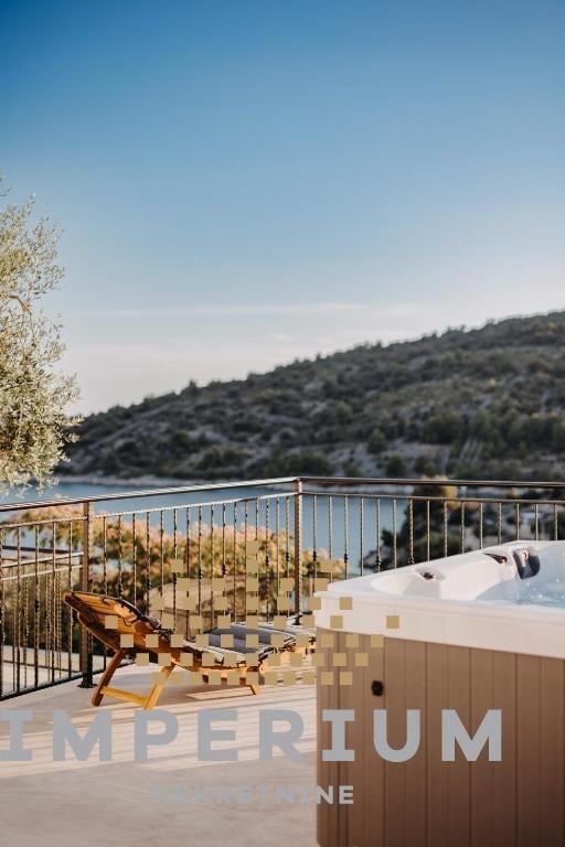 Modern deck with hot tub overlooking lake and forested hillside under clear blue sky