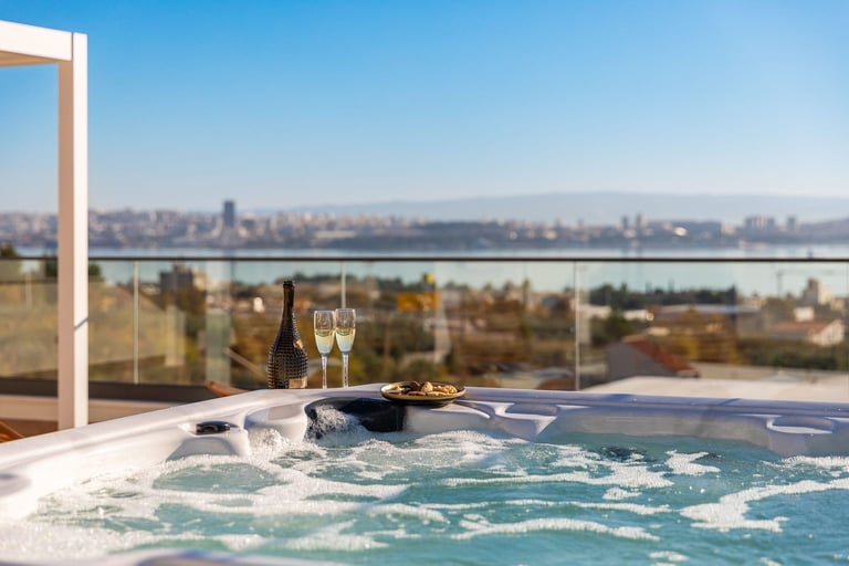 Hot tub on terrace overlooking city skyline and river with champagne glasses